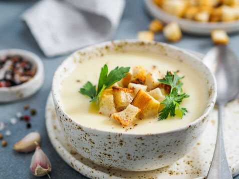 Auf dem Bild ist eine schmackhafte Suppe in einer dekorativen Schüssel mit Croutons und frischer Petersilie zu sehen.