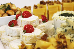 Auf dem Bild sind verschiedene Käsesorten, dekoriert mit Erdbeeren, sowie Snacks zu sehen.