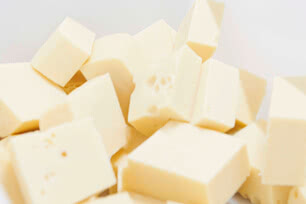 Auf dem Bild sind mehrere quadratische Stücke von weißem oder hellem Käse zu sehen.