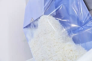 Auf dem Bild ist ein Kunststoffbeutel zu sehen, der mit weißem, geriebenem Material gefüllt ist.