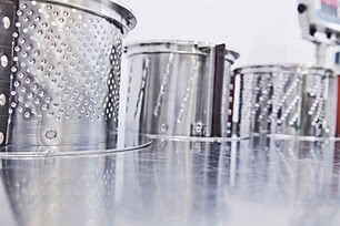 Auf dem Bild sind mehrere metallische Behälter mit perforierten Seiten zu sehen.