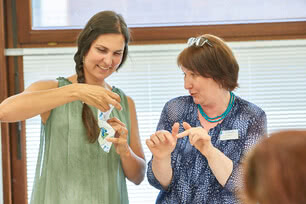 Auf dem Bild sind zwei Frauen zu sehen, die miteinander sprechen und anscheinend etwas demonstrieren oder erklären.