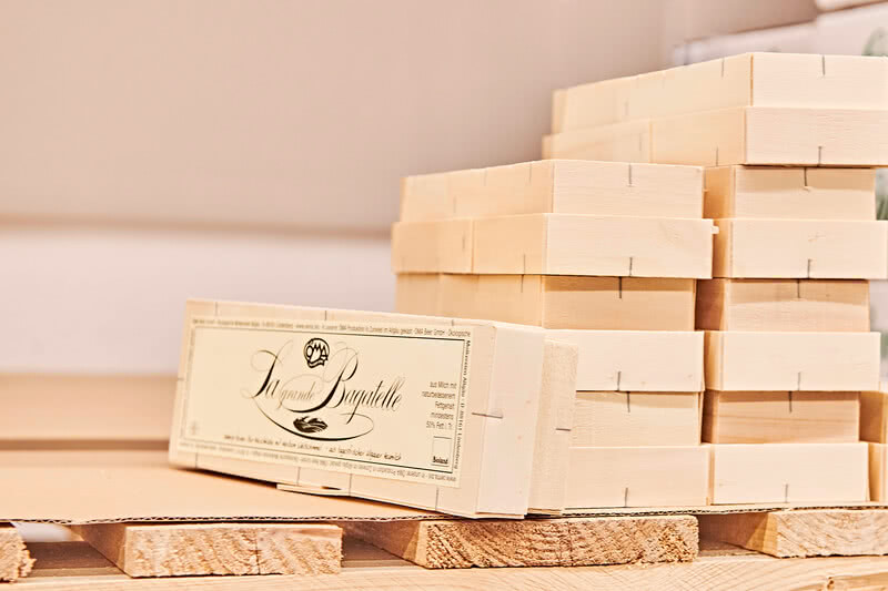 Auf dem Bild sind Stapel von Holzblocken sowie eine Verpackung mit dem Titel „La grande Bagatelle“ zu sehen.
