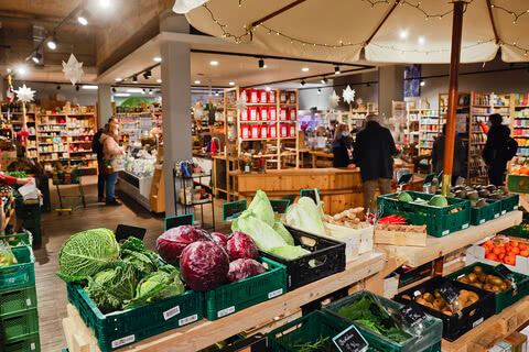 Auf dem Bild ist ein lebhafter Markt mit verschiedenen frischen Lebensmitteln und Produkten zu sehen.