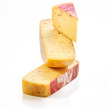 Auf dem Bild sind mehrere Stücke Käse mit einer roten Verpackung und einer Chili-Gewürzmischung zu sehen.