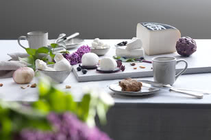 Das Bild zeigt eine ansprechend dekorierte Tischszene mit verschiedenen Käsesorten, frischen Zutaten und Tellern.