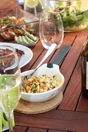 Auf dem Bild ist ein gedeckter Tisch mit verschiedenen Speisen und Getränken, darunter Salate, eine Schüssel mit einer Mischung und ein Glas Sekt zu sehen.