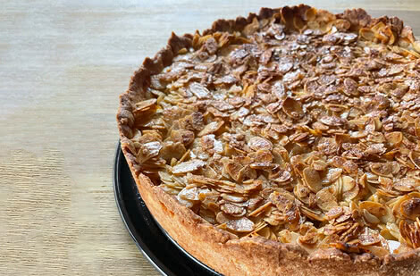 Auf dem Bild ist ein frisch gebackener Kuchen mit einer Schicht aus Mandelsplittern zu sehen.