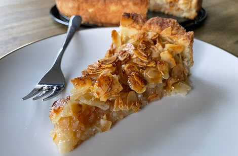 Auf dem Bild ist ein Stück Kuchen mit einer Mandel- und Apfelfüllung auf einem Teller zu sehen.