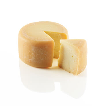 Das Bild zeigt einen Käselaib, aus dem ein Stück herausgeschnitten wurde.