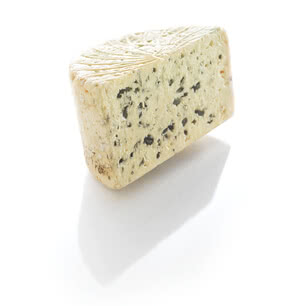 Auf dem Bild ist ein Stück Käse mit grünen und schwarzen Einsprenklungen zu sehen.