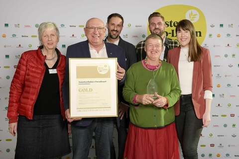 Auf dem Bild sind mehrere Personen zu sehen, die mit einer Auszeichnung für den Naturkostladen