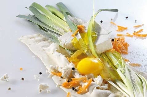 Auf dem Bild sind frische Zutaten wie Lauch, Eiklar, Kräuter und zerbröckelter Käse ansprechend angerichtet.